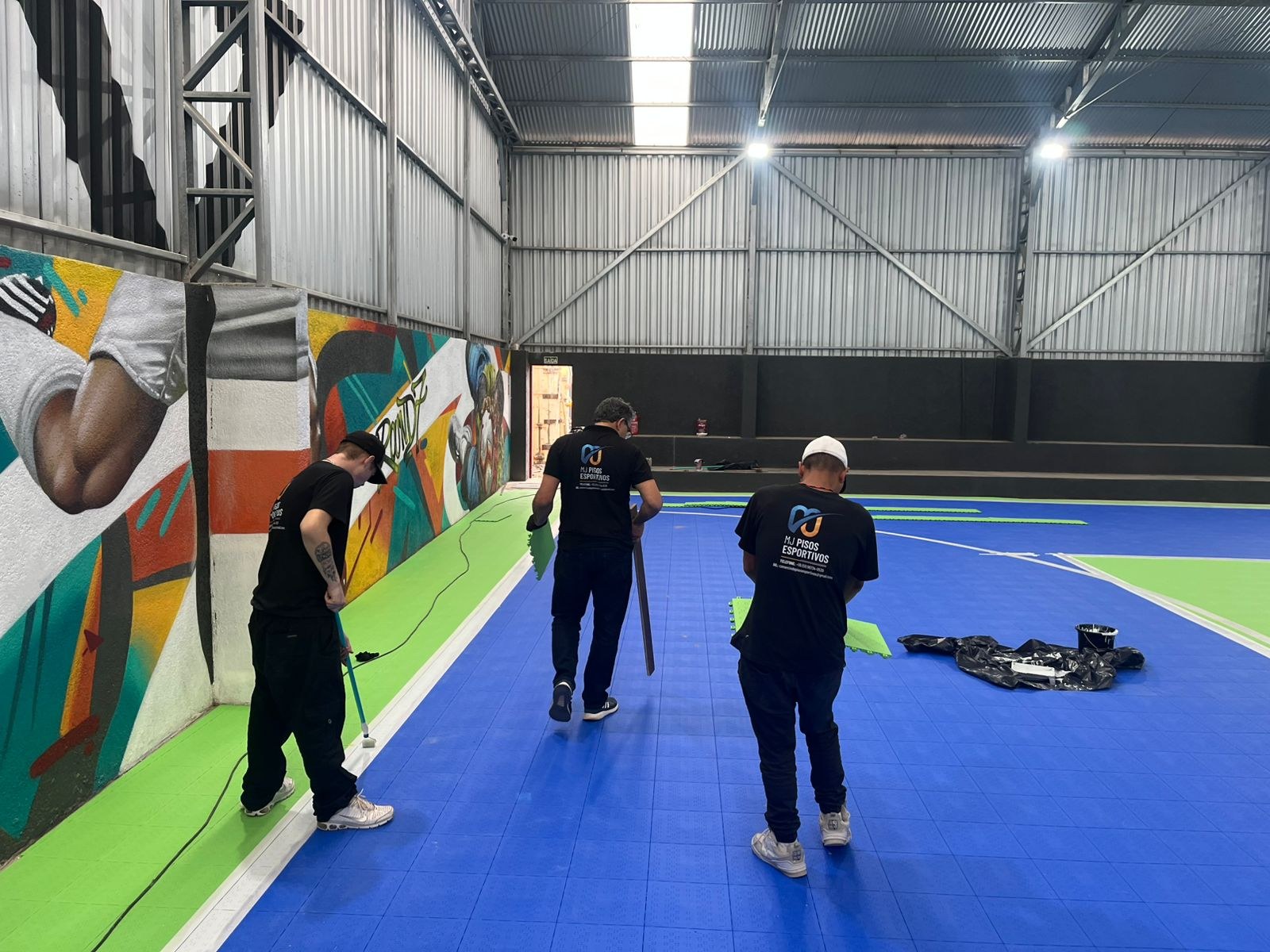 Equipe trabalhando na montagem do piso ao lado da quadra